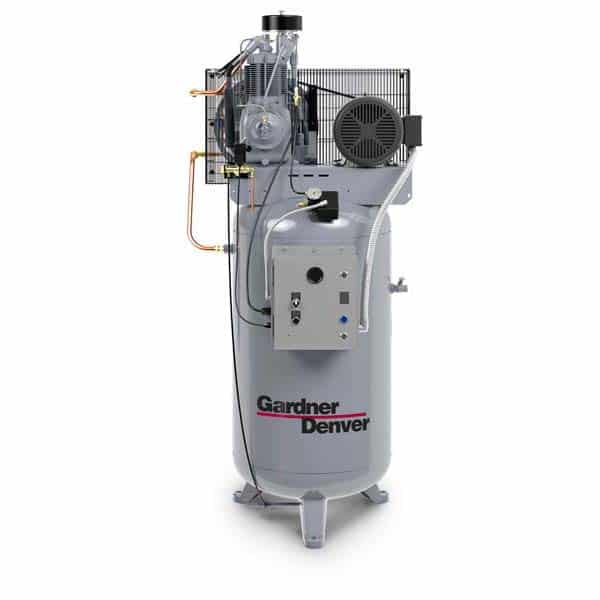 A vertical industrial air compressor with a control panel, motor, and pipes labeled Gardner Denver stands on a cylindrical tank.