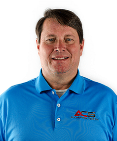 A middle-aged man with short brown hair smiles at the camera, wearing a bright blue polo with a red and gray ACG logo on white background.