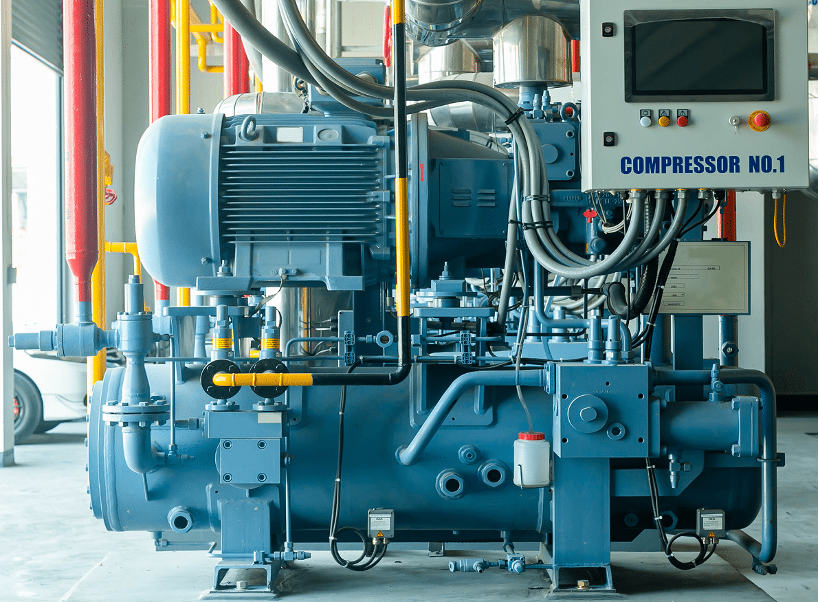 A large industrial blue compressor labeled COMPRESSOR NO.1 with control panel, wires, and pipes, indoors among red and yellow pipes.